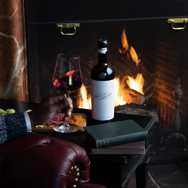 A bottle of Highest Beauty on a table next to a fireplace.